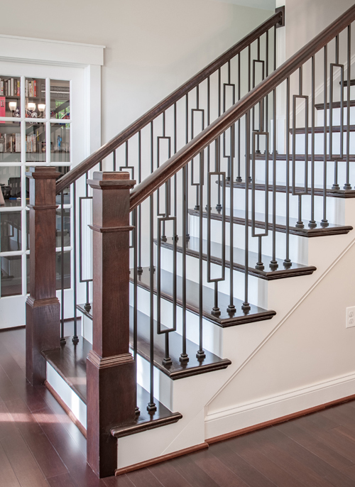 Wooden staircase with square newel post and iron balusters.