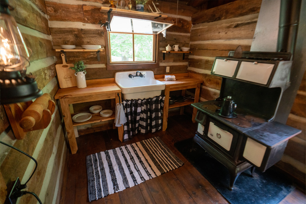 A small cabin with an old fashioned wood-burning stove. 