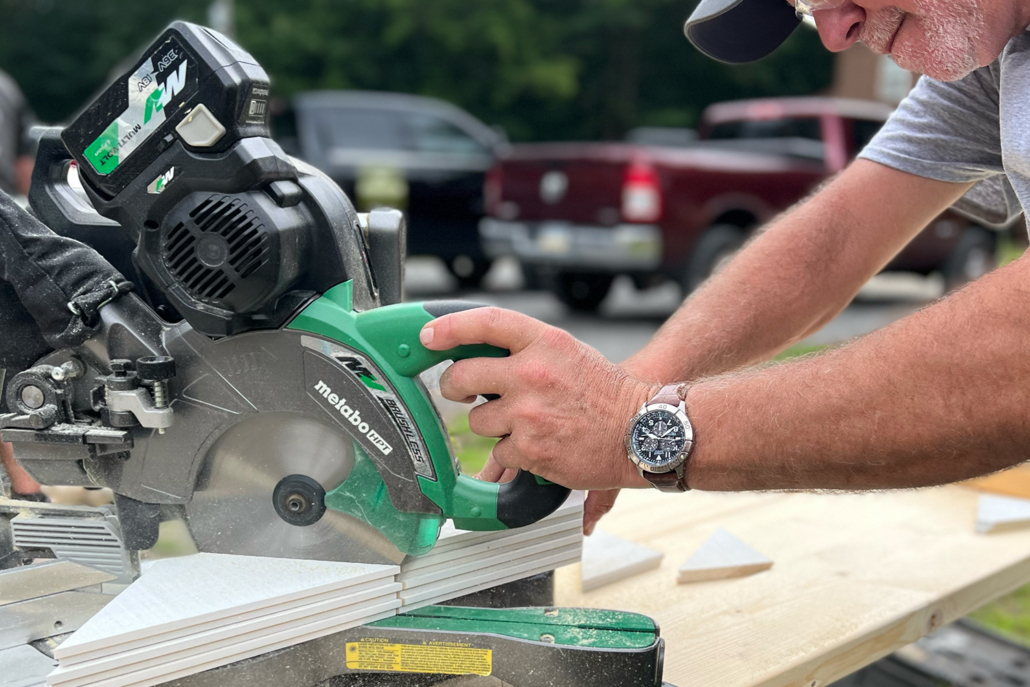 A man making an angled cut with a miter saw. 