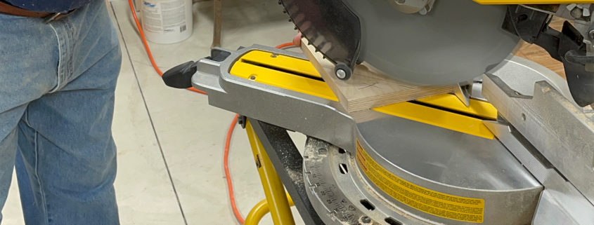 A sliding compound miter saw being used to make a cut.