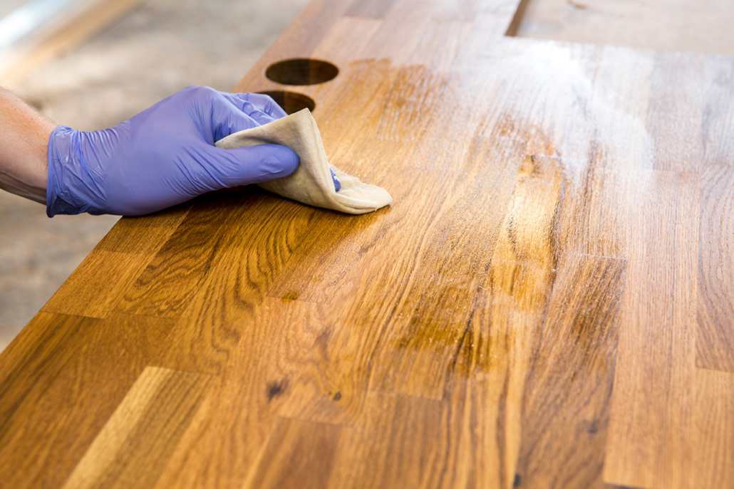 A person applying mineral oil to a butcher block countertop.